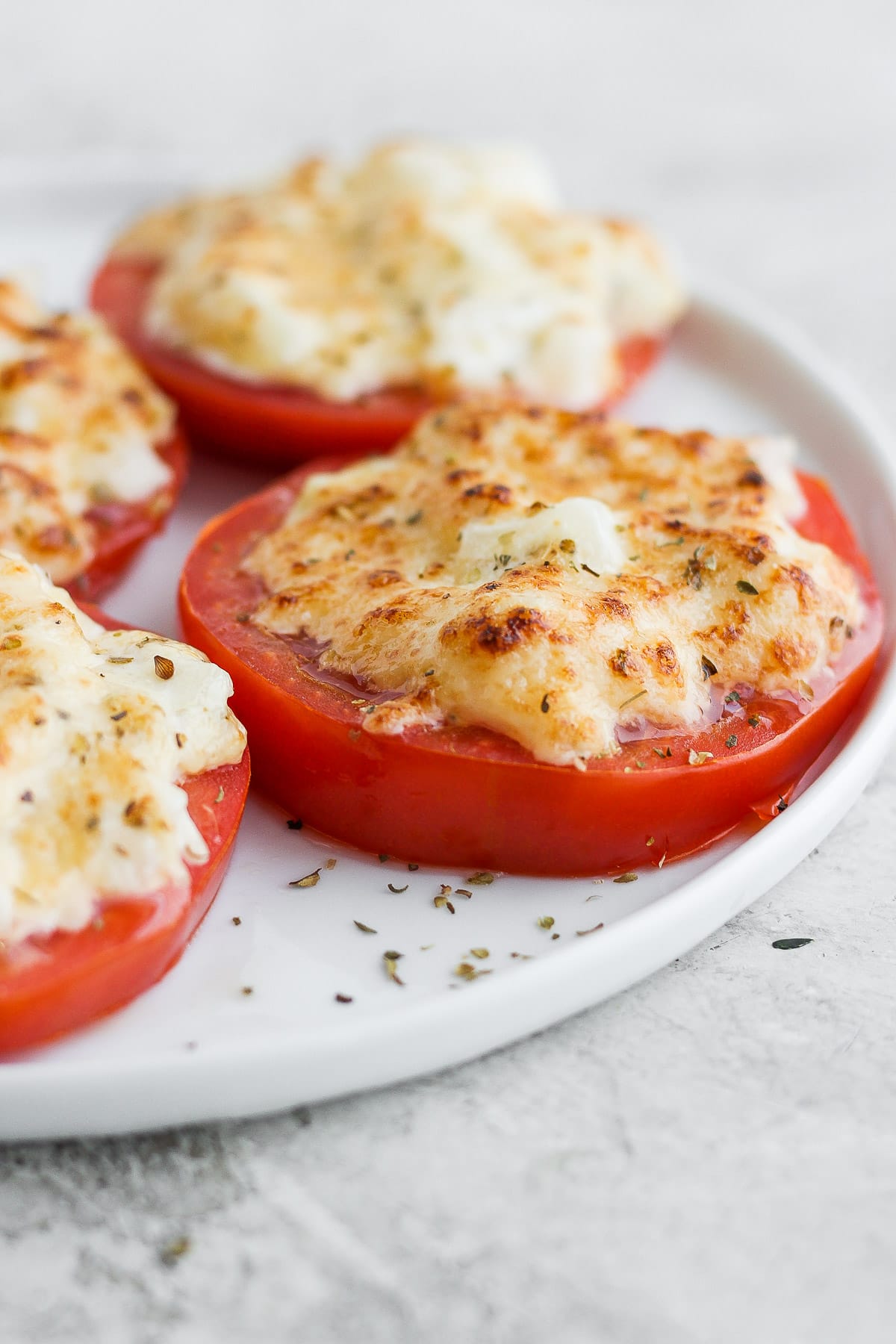 Broiled tomatoes on a white plate. 