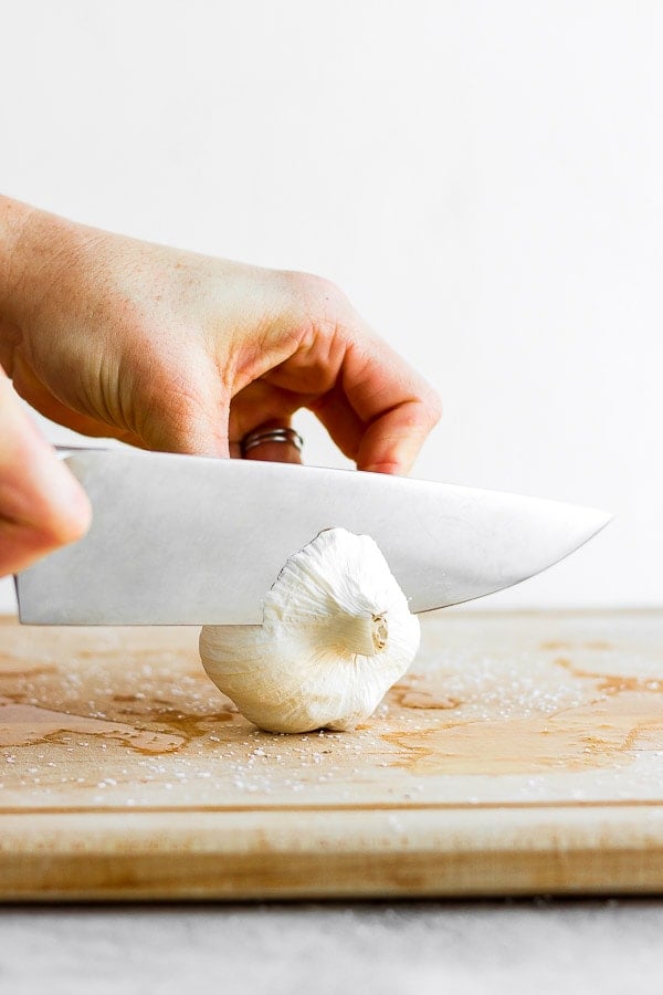 Showing how to cut of one end of a head of garlic. 