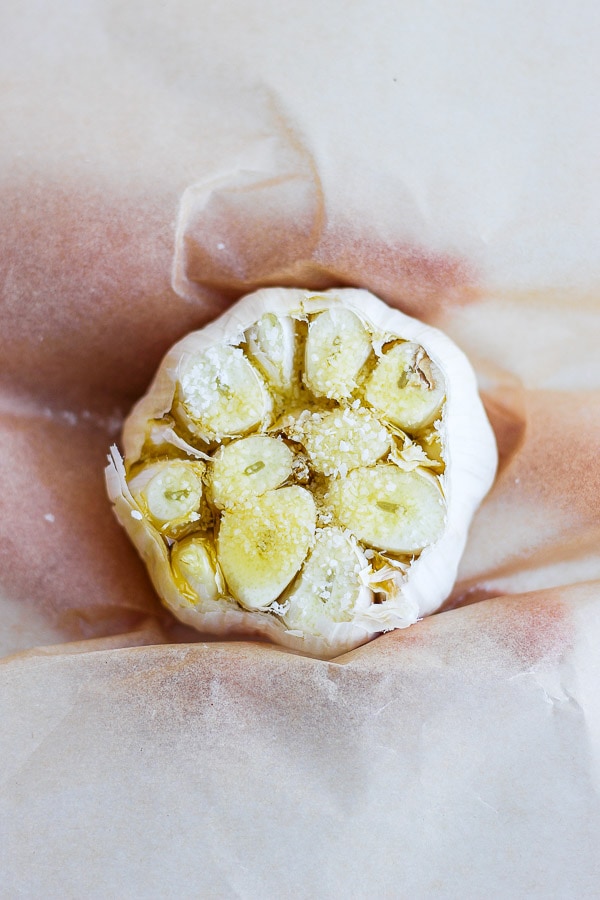 A head of garlic with one end cut off covered in oil and salt. 