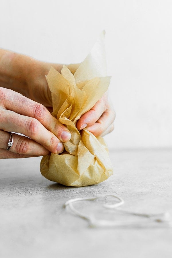 Showing how to wrap garlic in parchment paper. 