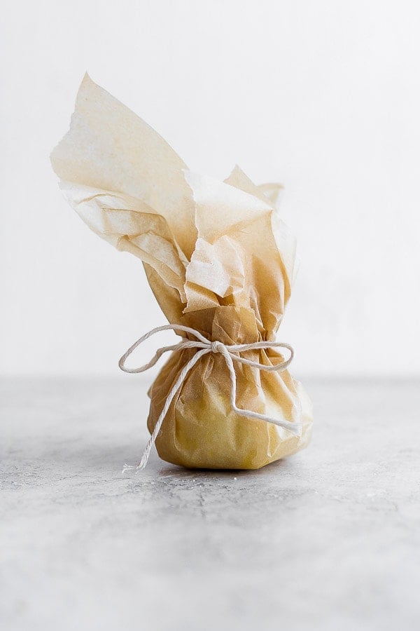 Roasted garlic tied up in parchment paper. 