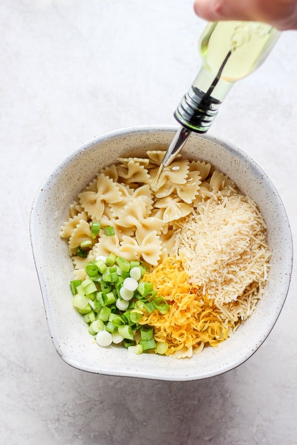 Someone pouring olive oil into lemon pasta.