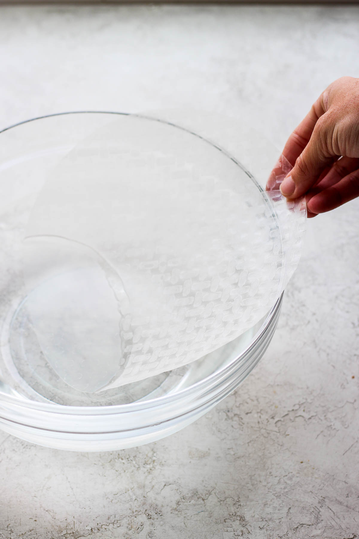 Picture of someone dipping a rice paper wrapper into some water. 