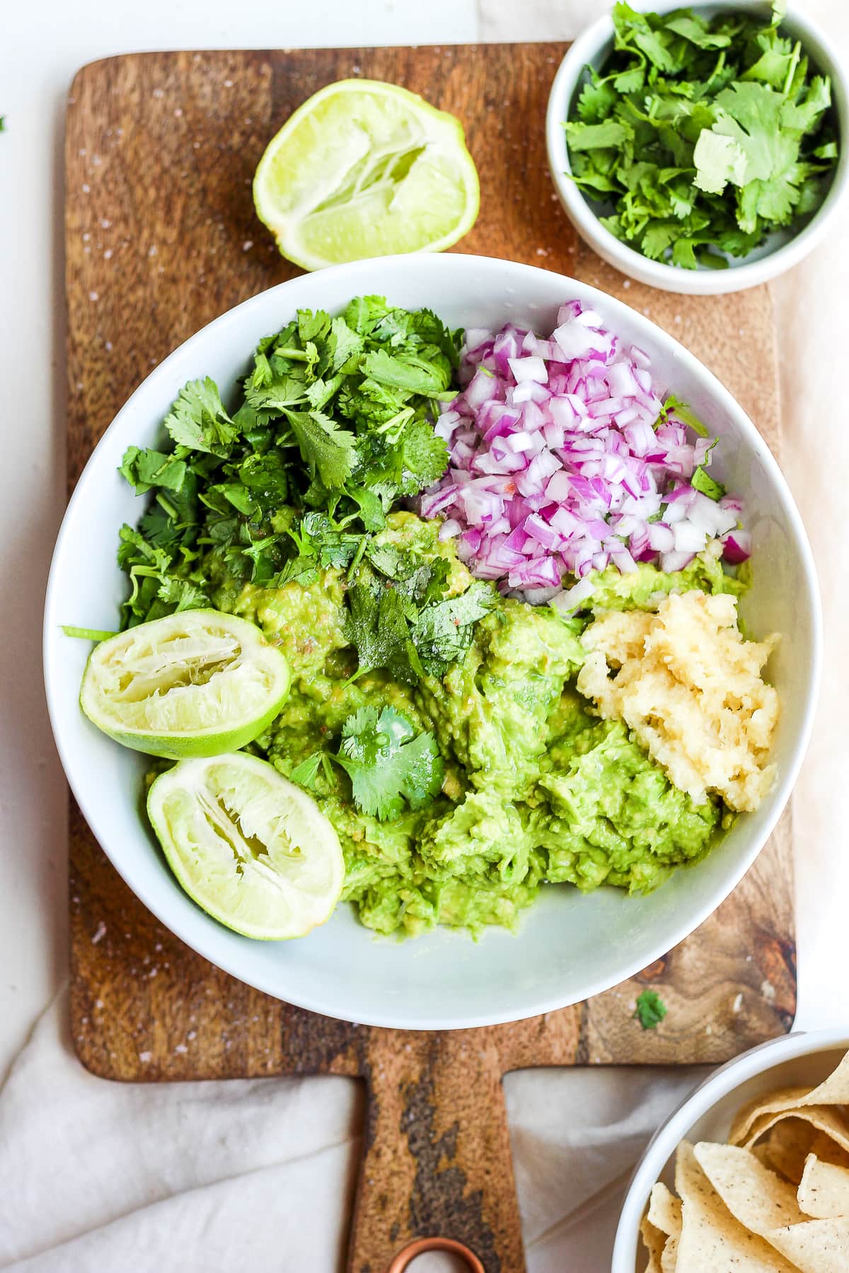 Smashed avocado in a bowl with the other ingredients added.