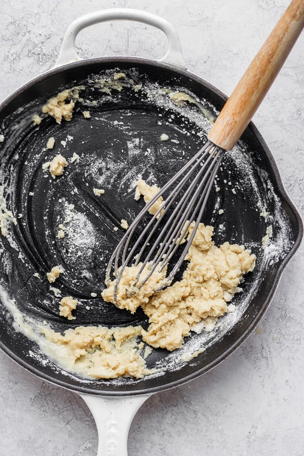 A whisk mixing the flour and melted butter together to make a paste or roux.