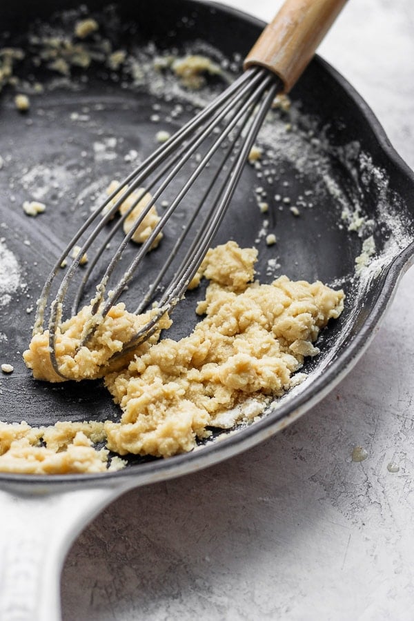 A whisk mixing together flour and melted butter into a paste or roux.