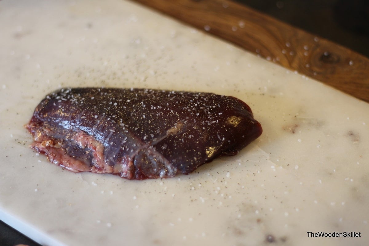 One duck breast seasoned with salt and pepper.