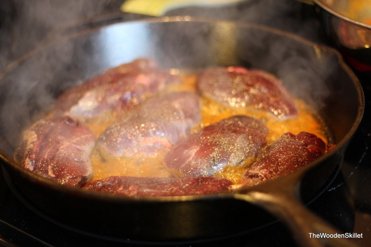 All of the duck breasts searing in the cast iron skillet.