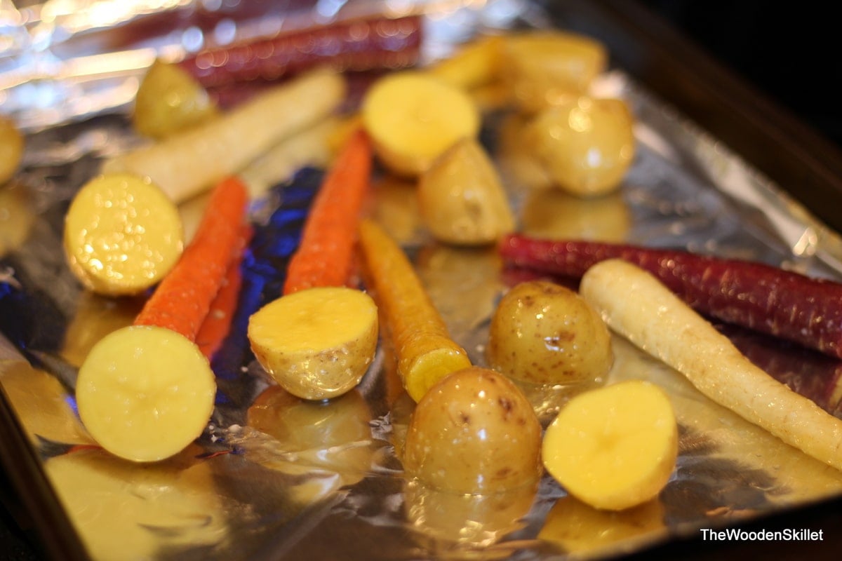 Carrots and potatoes on a foil-lined baking sheet after being tossed in oil and salt.