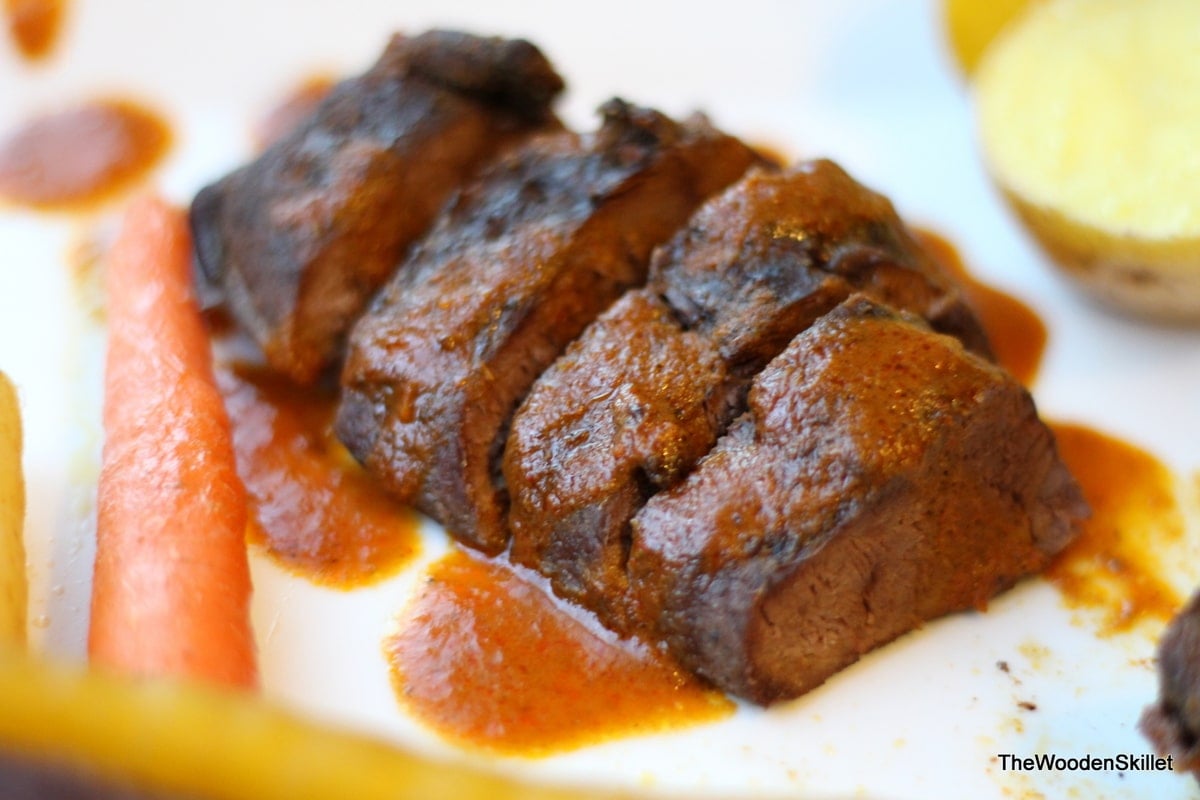 A fully cooked duck breast on a white plate and cut into slices.