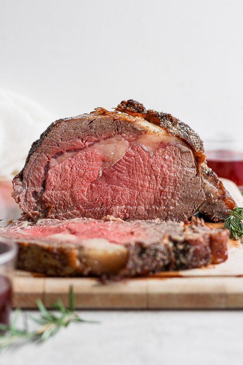 Prime rib on a cutting board with a slice cut off. 