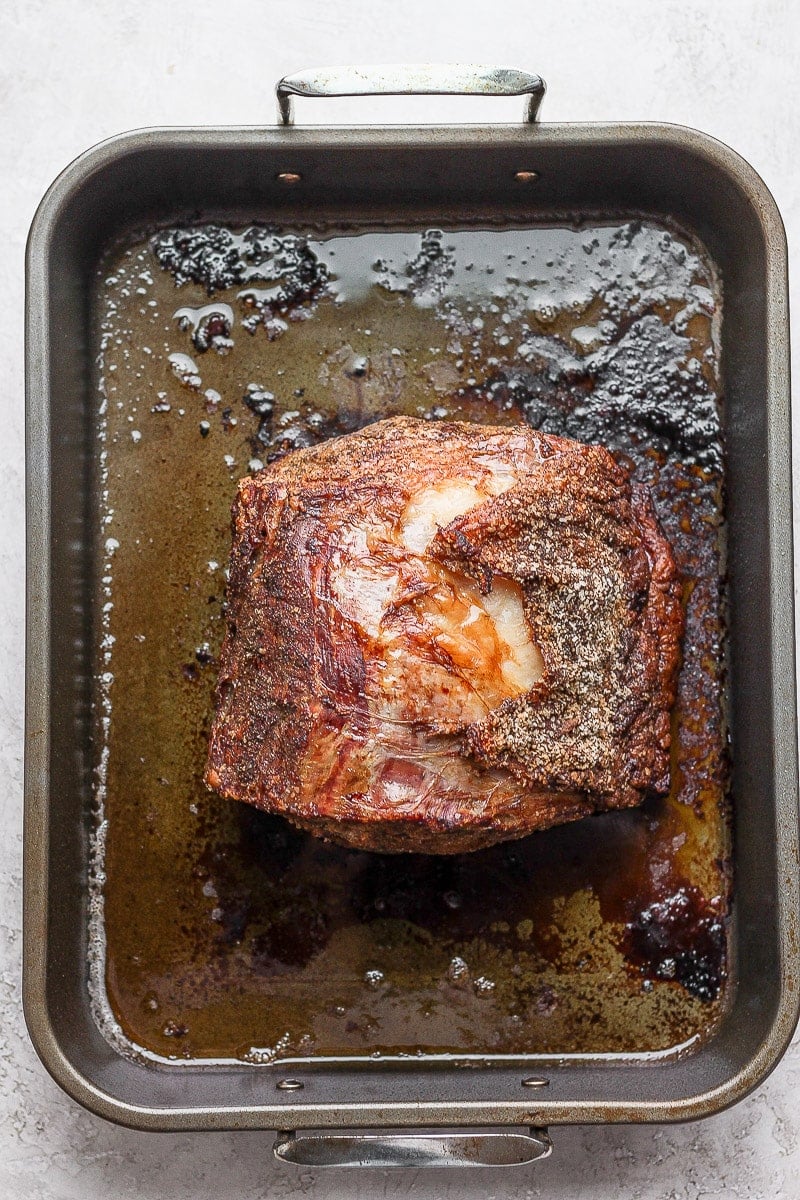 Prime rib with salt and pepper rub sitting in roasting pan, cooked. 