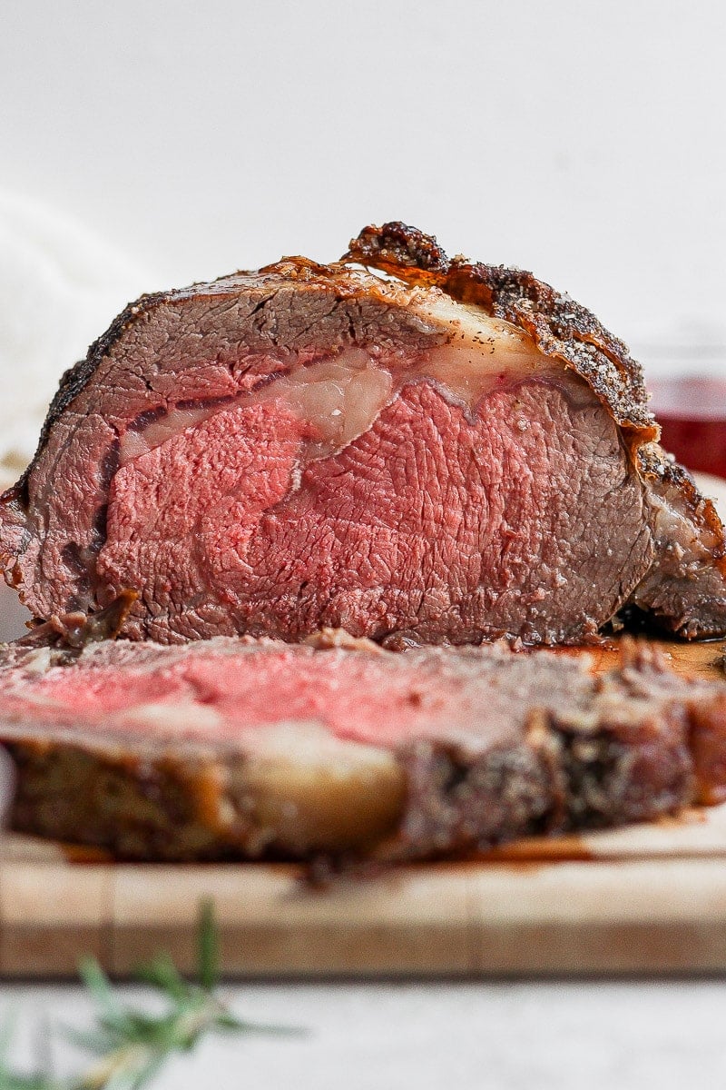 Standing rib roast on a cutting board with a slice cut off. 