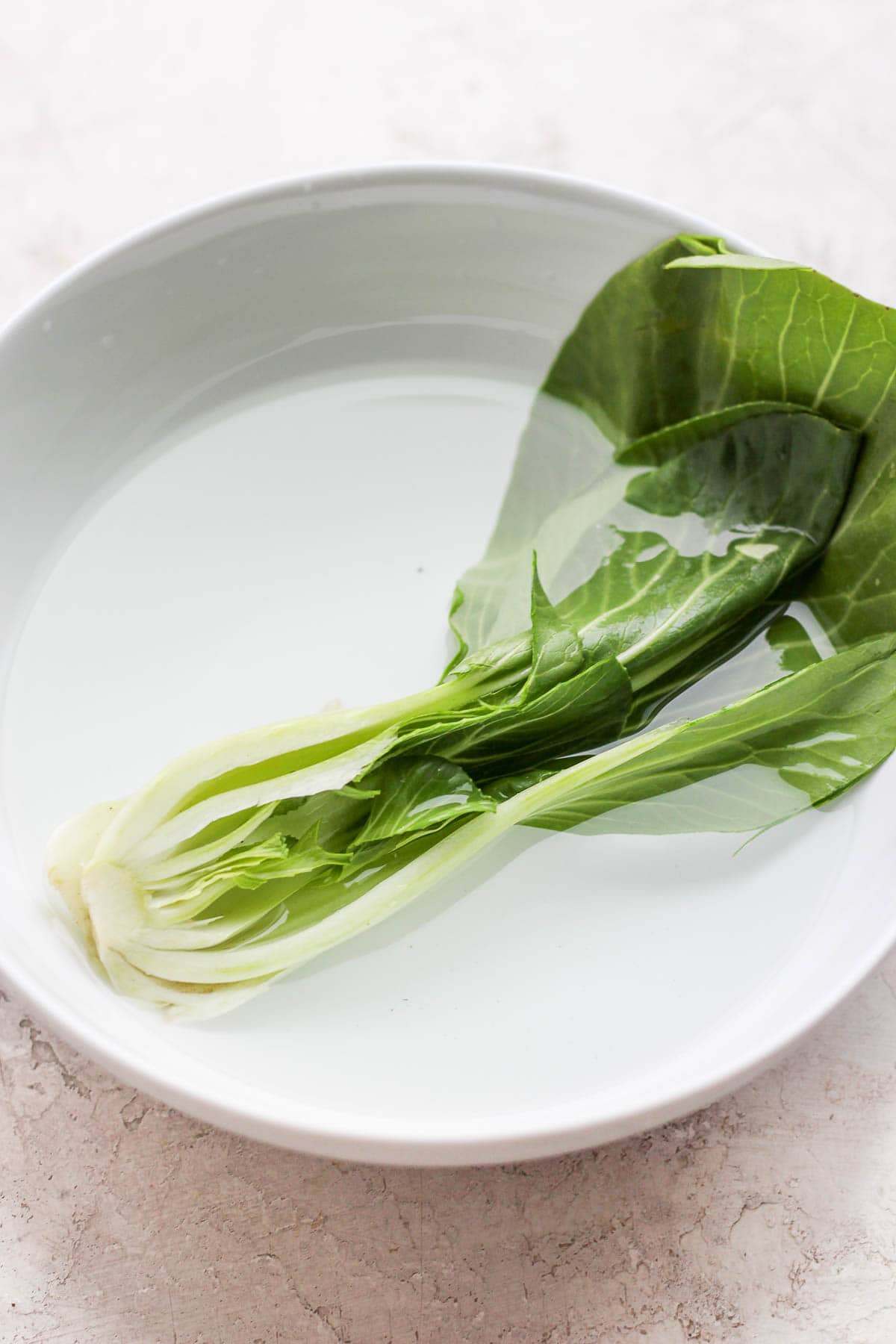 A halved baby bok choy soaking in some water. 