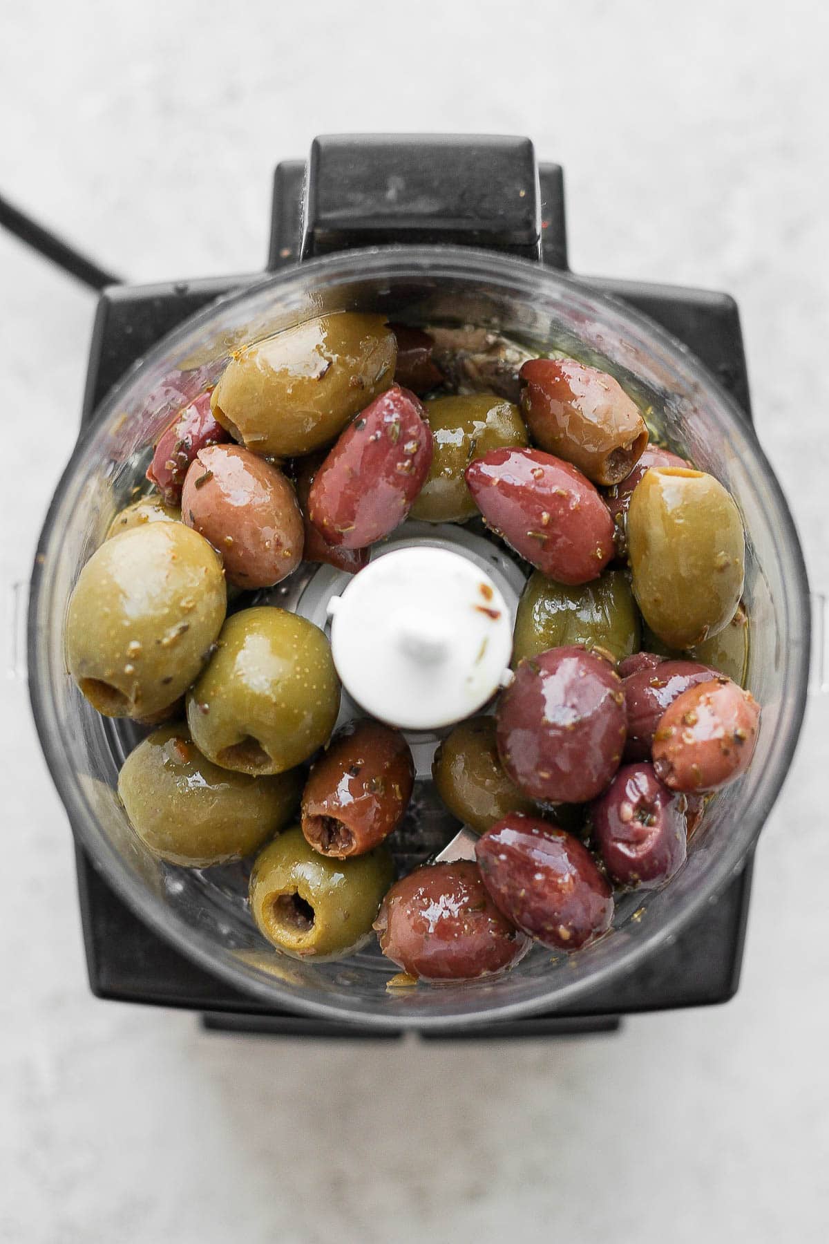 Top shot of a food processor with mixed olives inside. 