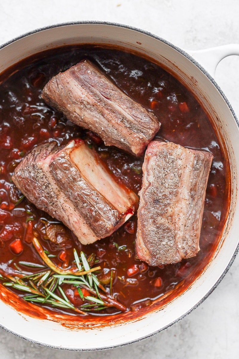 Short ribs sitting on top of the braising liquid.