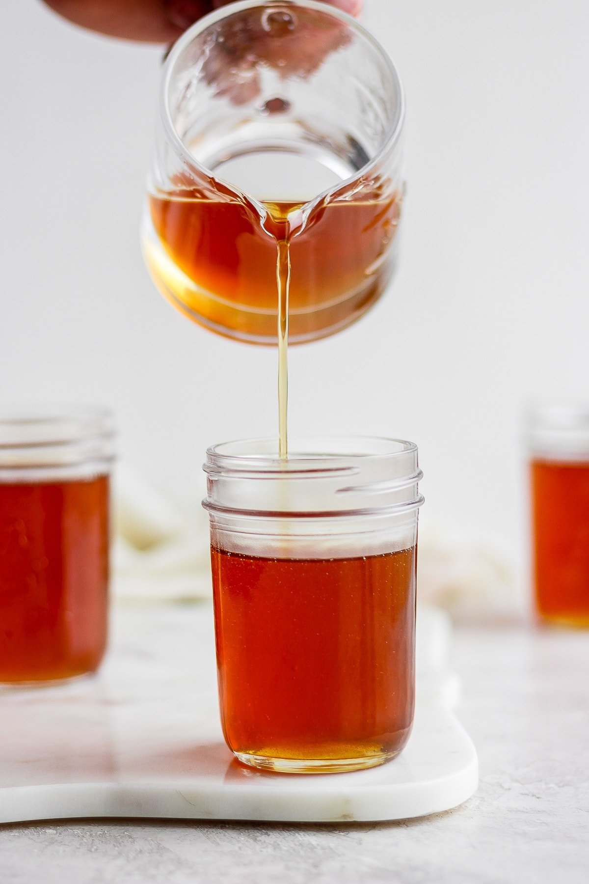 Someone pouring maple syrup into mason jars. 