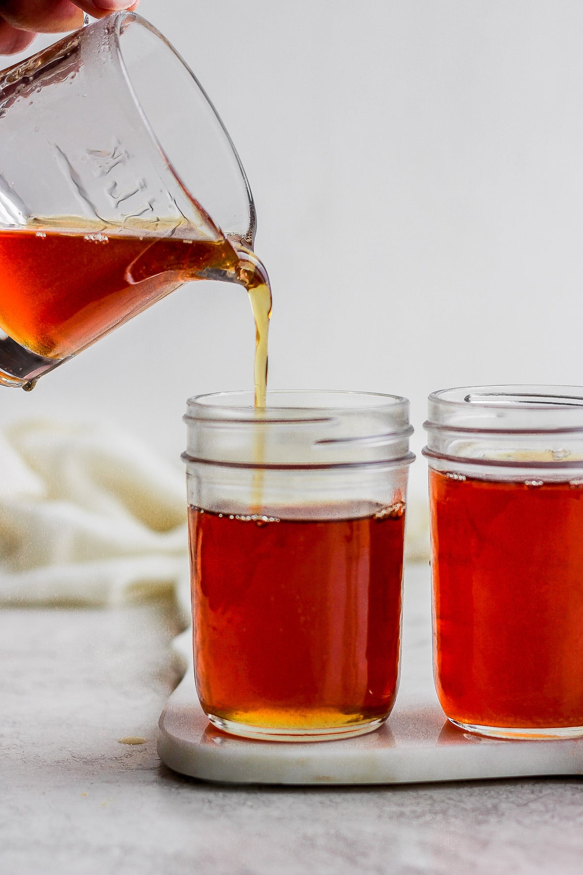 Someone pouring maple syrup into mason jars. 