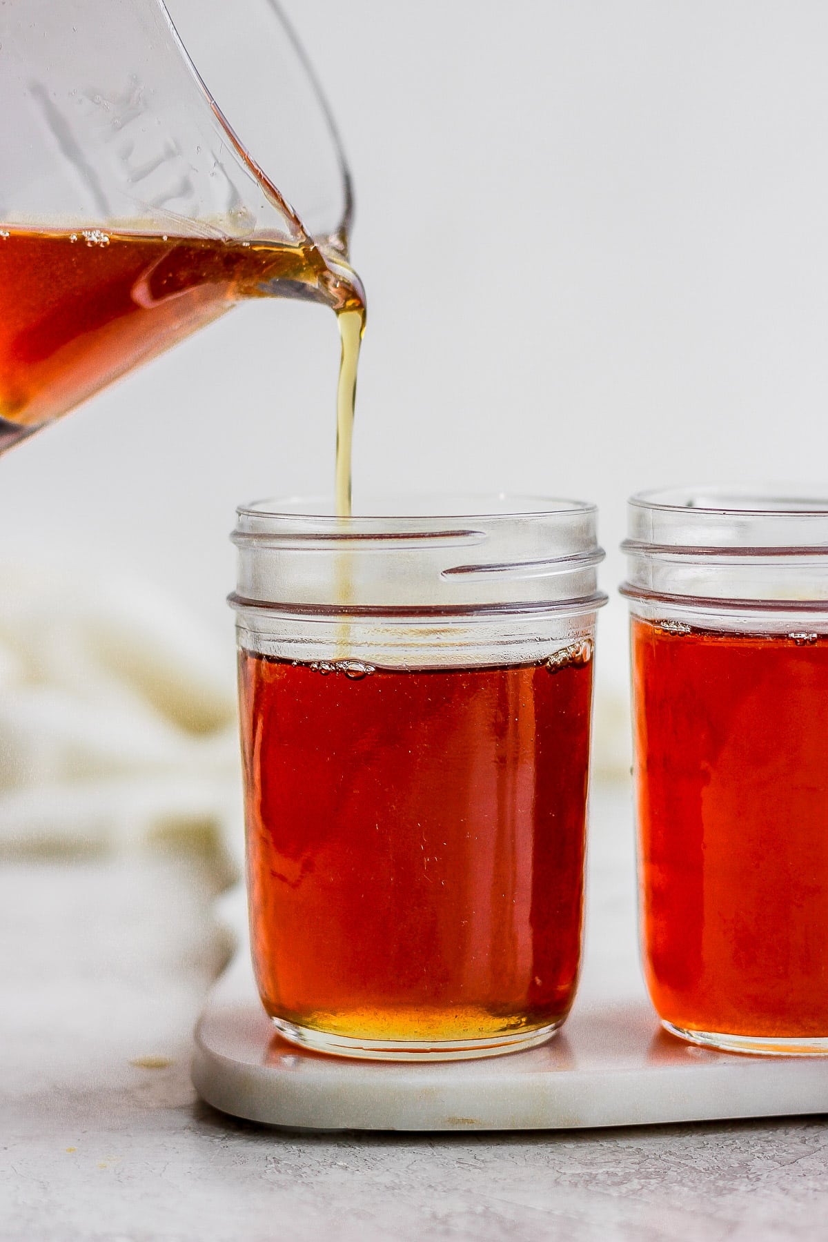 Someone pouring maple syrup into mason jars. 