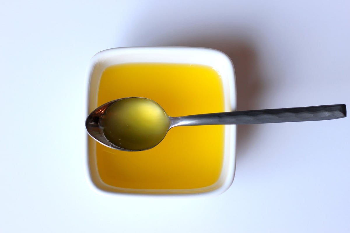 A spoon of schmaltz over a small bowl of schmaltz. 