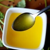 A bowl of rendered chicken fat with a spoon lifting some out.