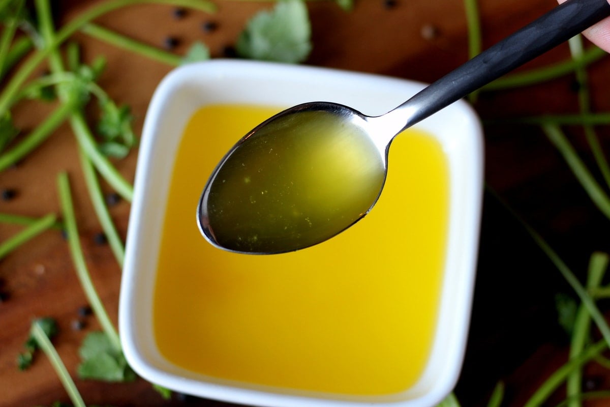 A spoon of schmaltz over a small bowl of schmaltz. 