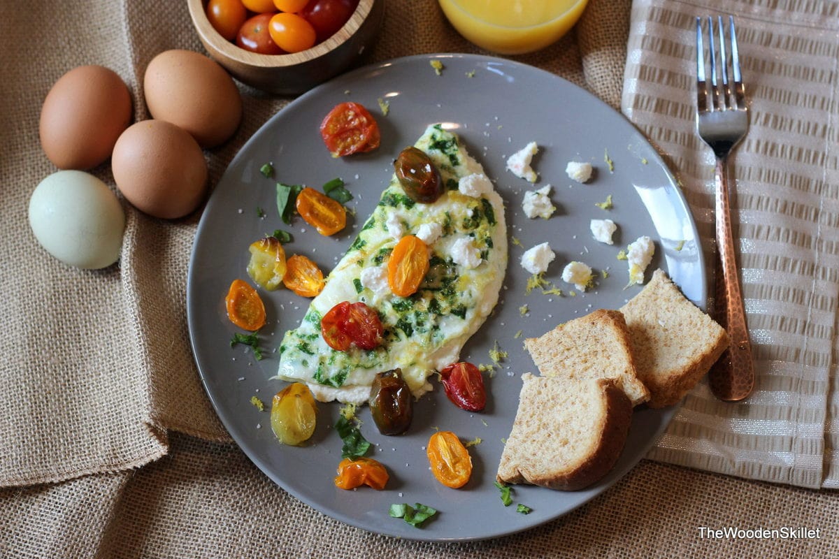 Plate with a goat cheese omelette, roasted tomatoes and toast. 