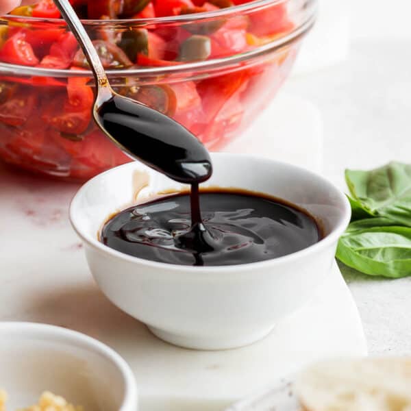 A bowl of balsamic glaze with a spoon lifting some up.