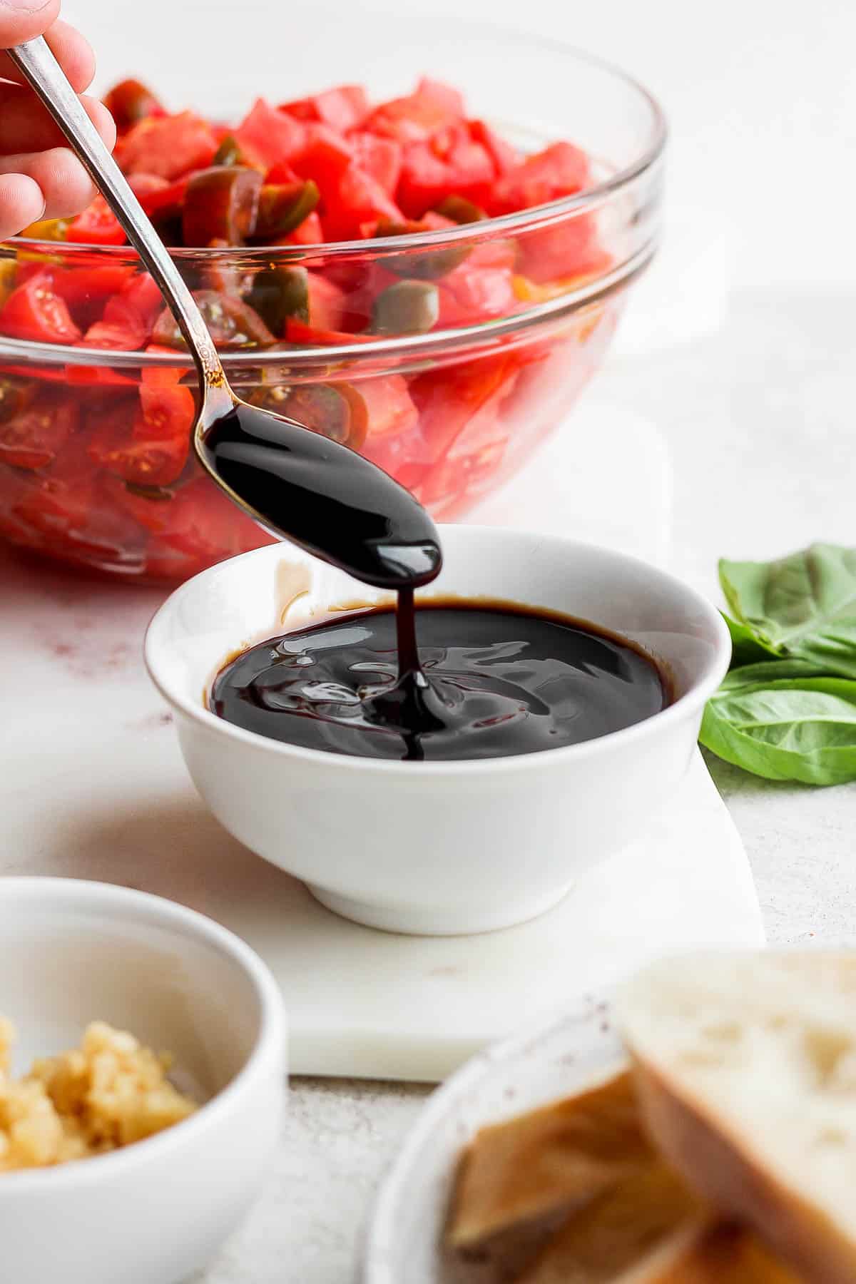 A spoon scooping balsamic glaze out of a small dish.