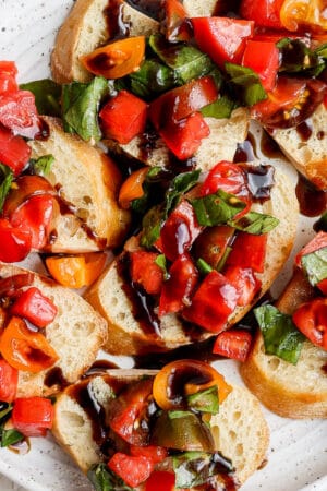 A plate of bruschetta drizzled with balsamic glaze.