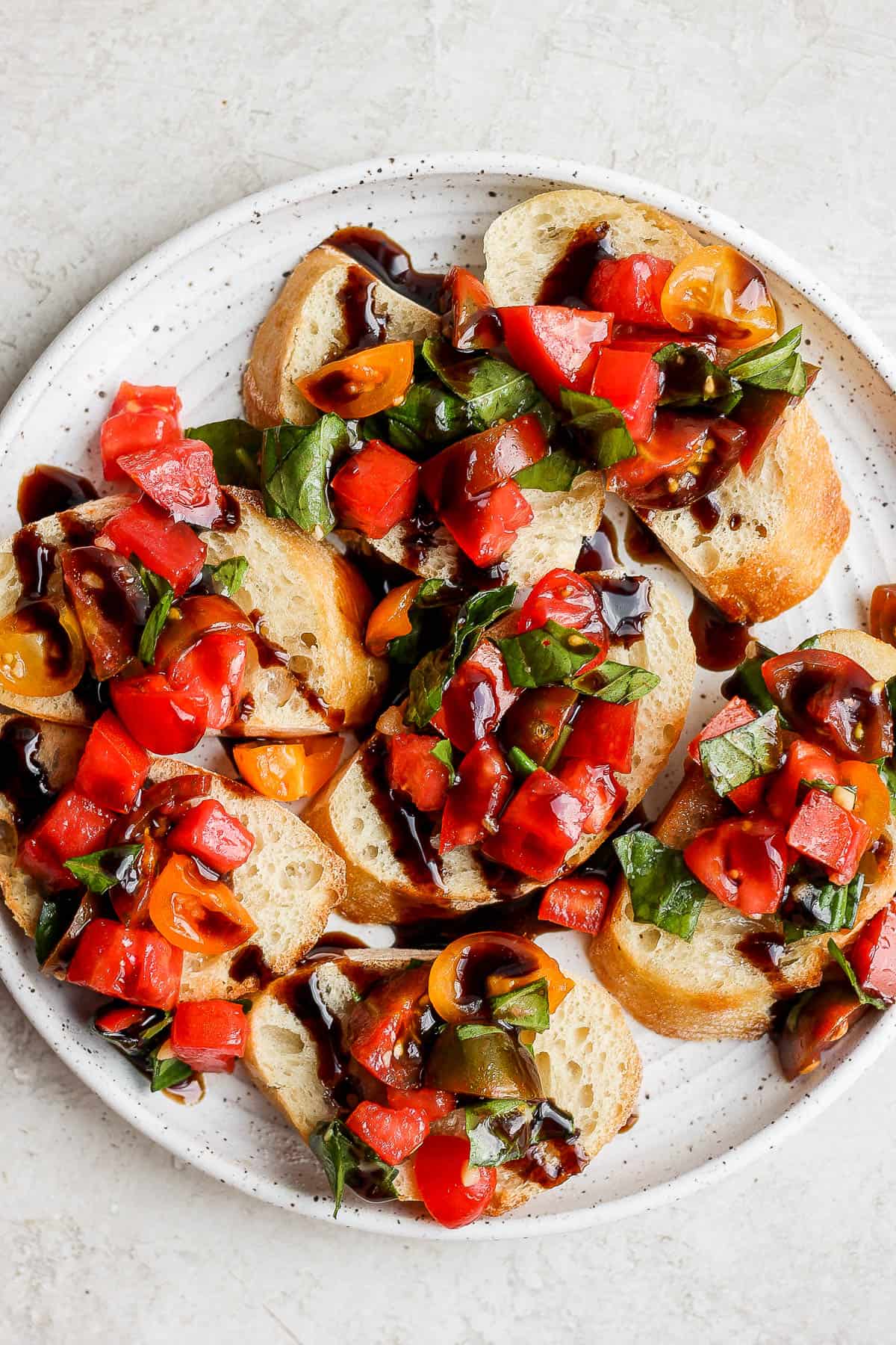 Crostini topped with fresh bruschetta on a white plate.