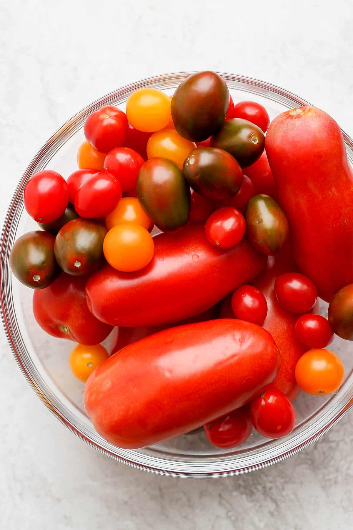 A mixing bowl full of different tomatoes.