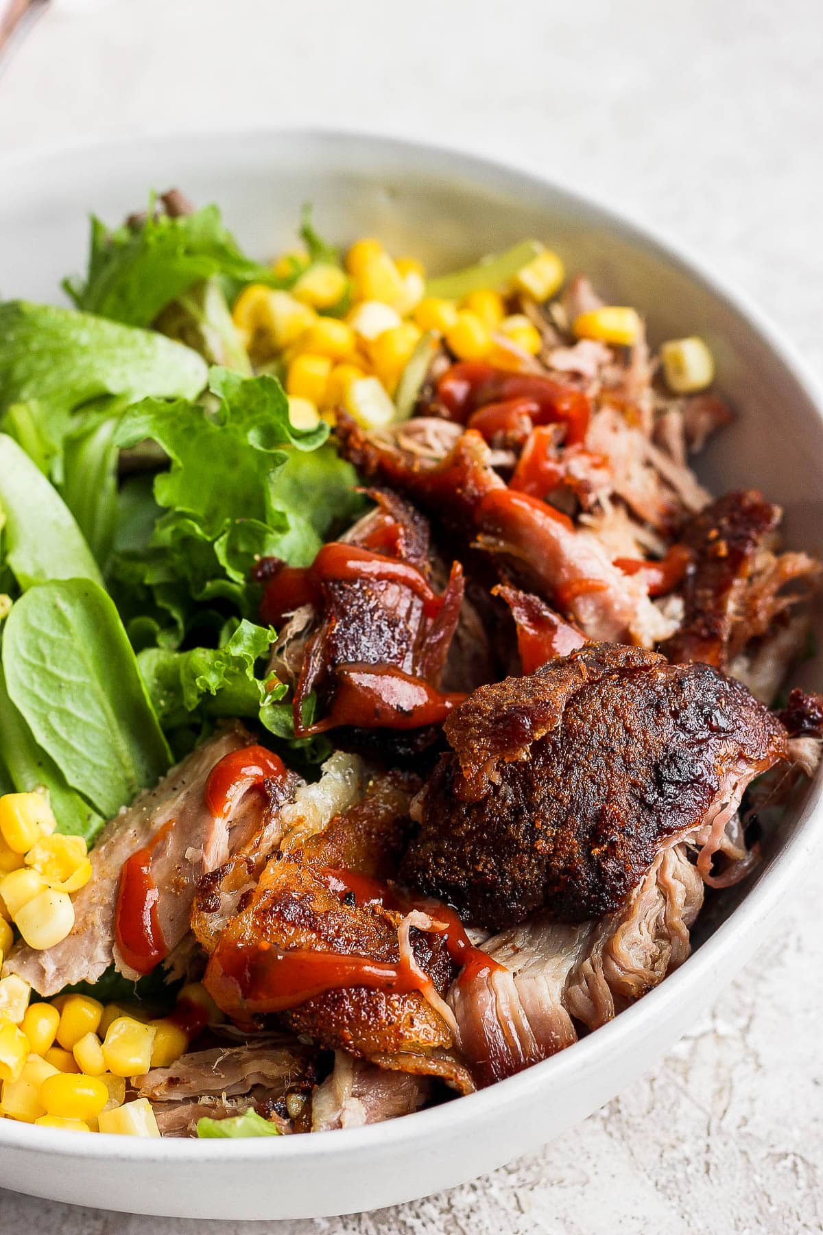 A pulled pork salad in a bowl with corn and avocado. 