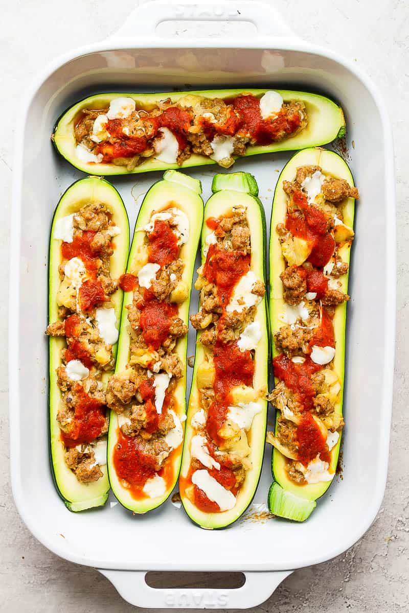 Baking dish filled with cooked, stuffed zucchini boats.