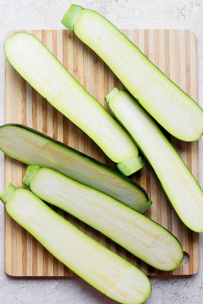 Several zucchini on a cutting board cut in half lengthwise.