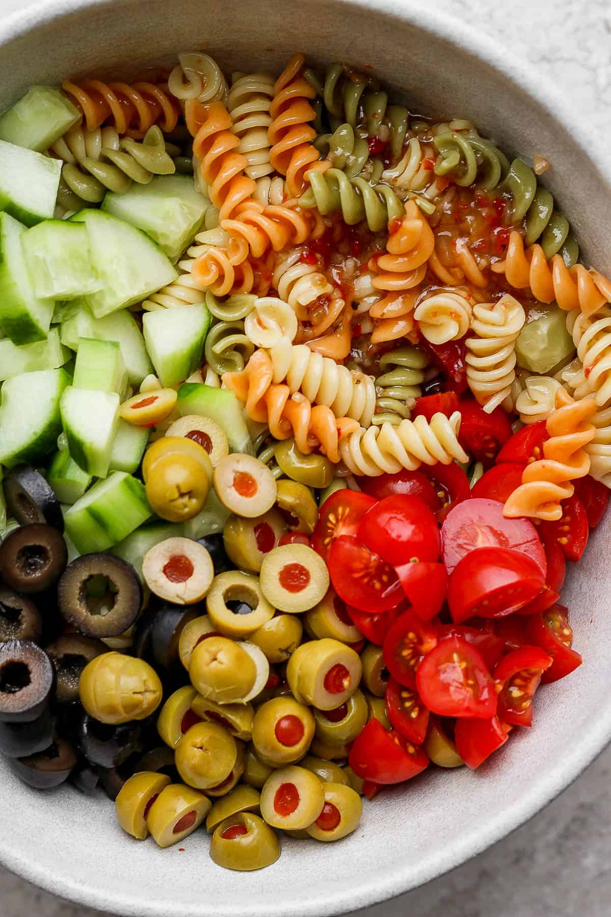 Close up of zesty italian pasta salad in a bowl, not mixed up yet. 