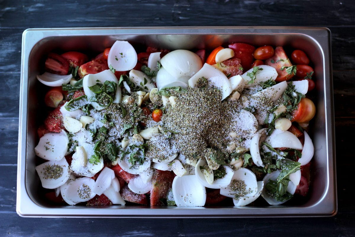 Large aluminum pan filled with herbs, spice and tomatoes. 