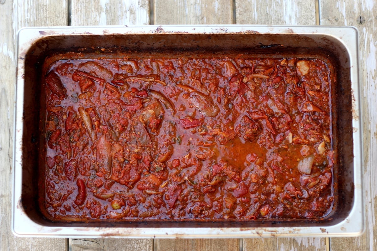 Large aluminum pan with roasted marinara sauce in it. 