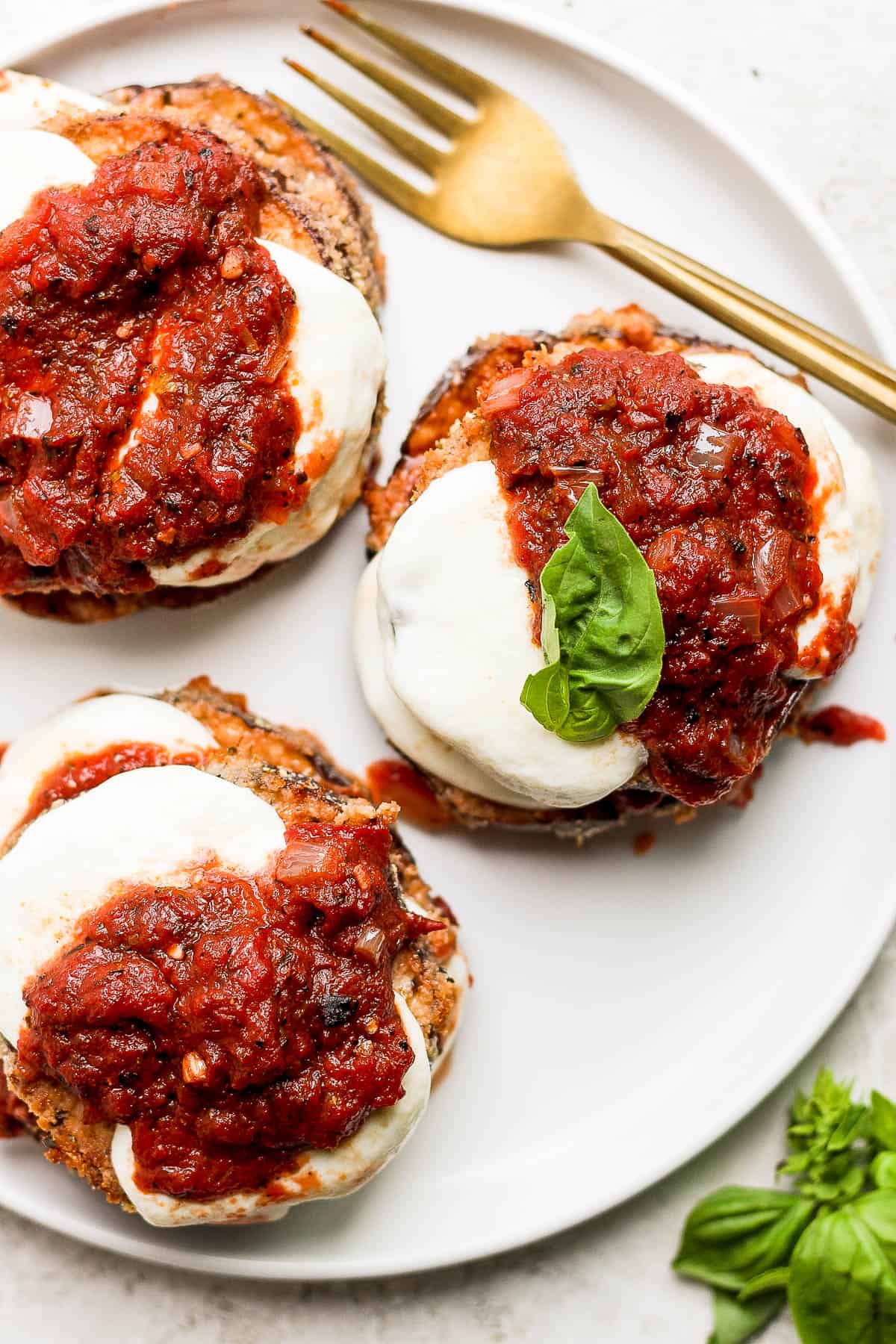 A top shot of a plate of stacks of baked eggplant parmesan.