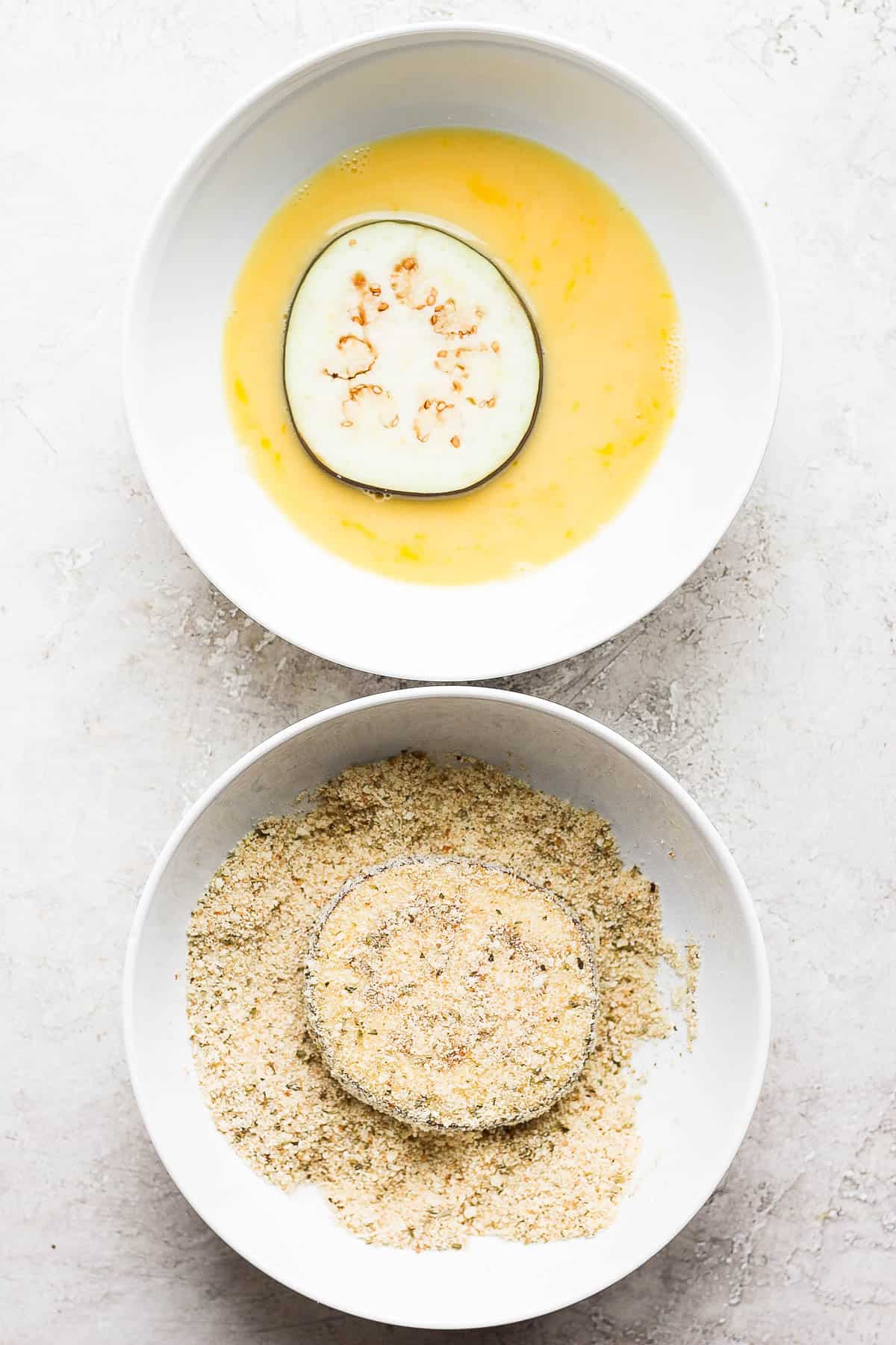 Two bowls, one with egg wash in it and one with a breadcrumb mixture in it. 