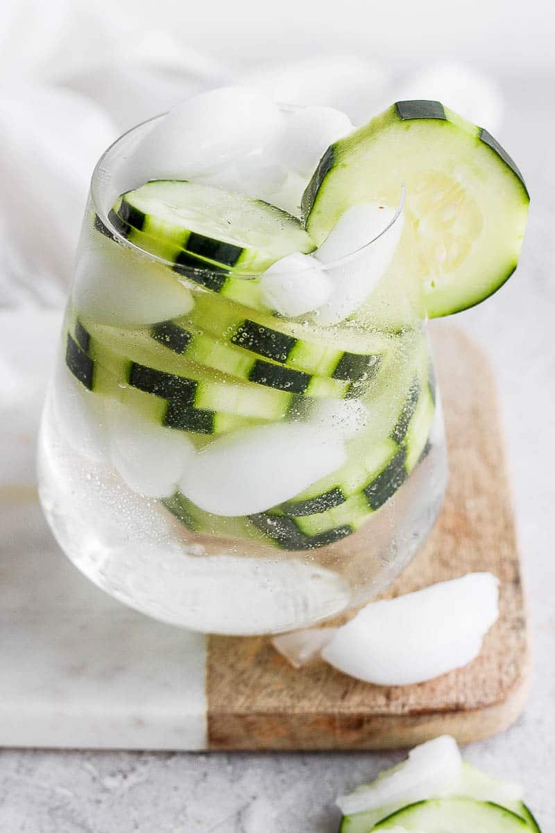 A cucumber vodka and water in a glass with cucumber slices inside. 