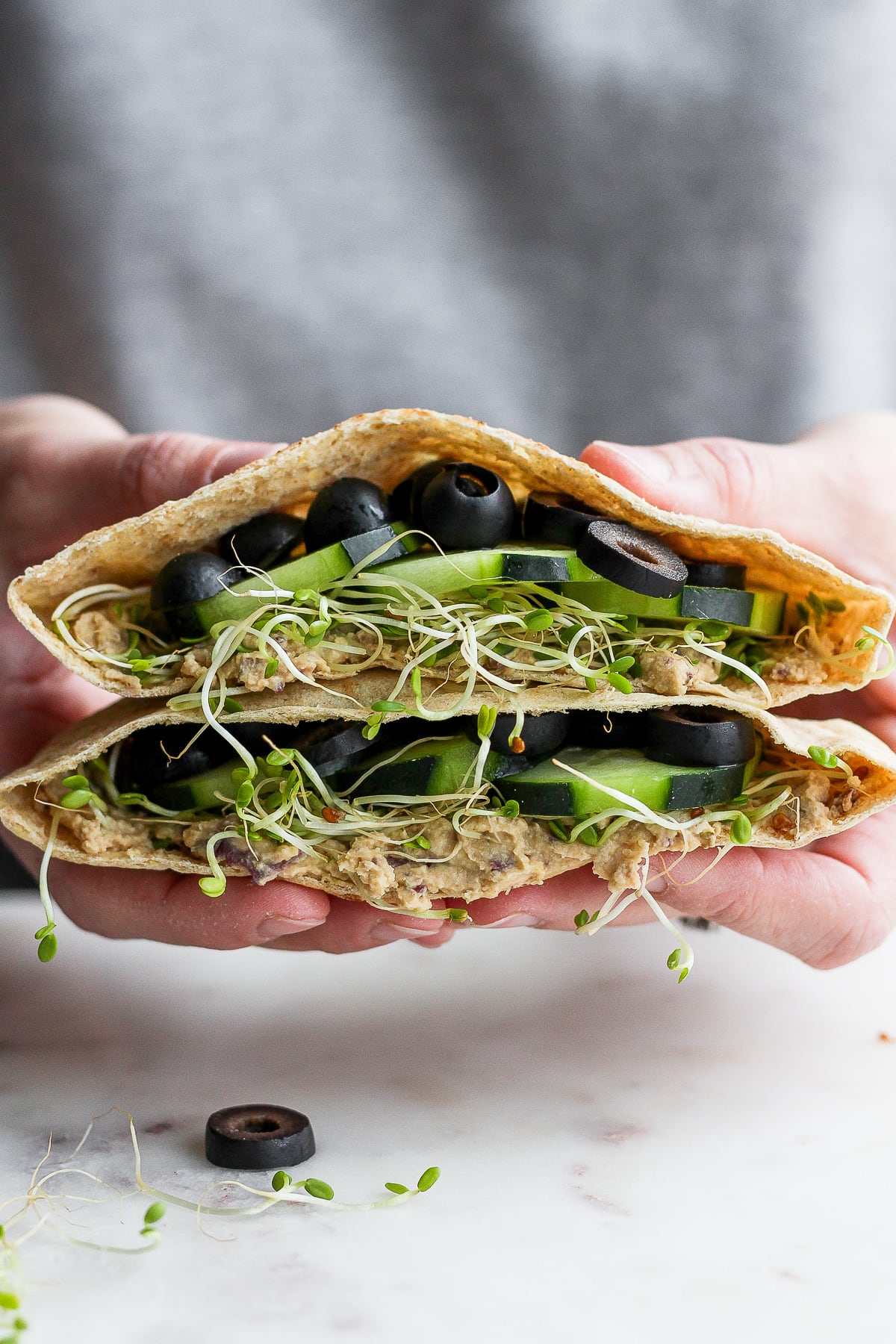 Someone holding two sides of a vegan pita sandwich. 