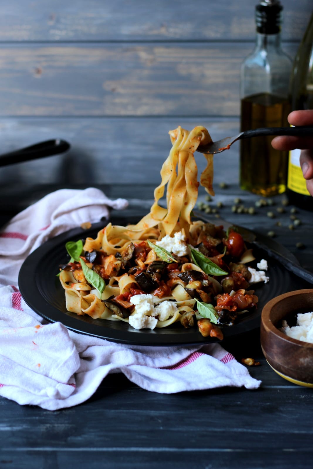 A fork pulling noodles of ragu up off the plate.