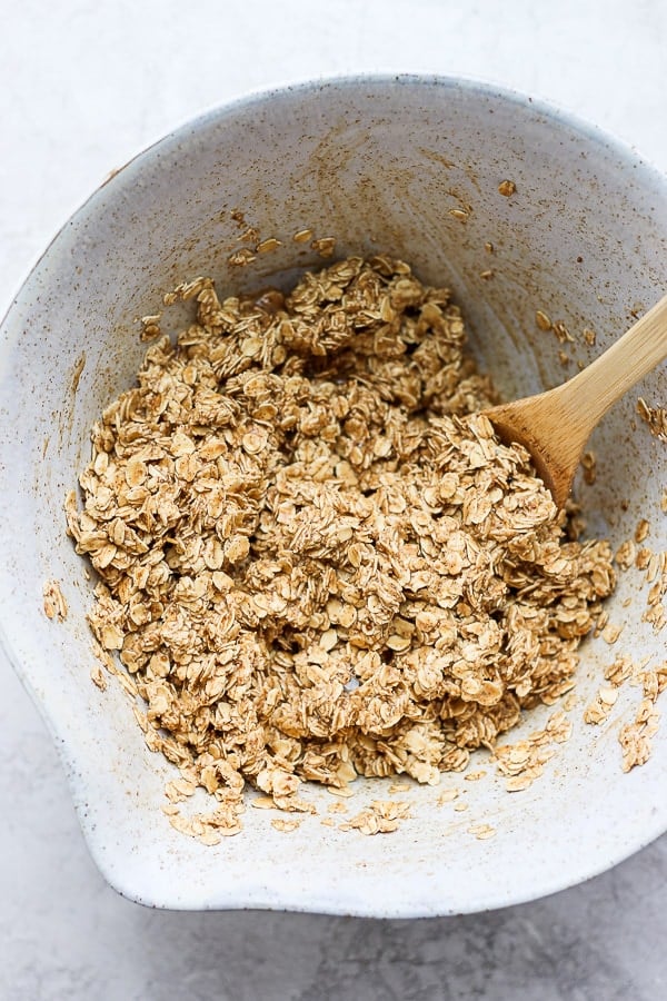 A large mixing bowl with the wet and dry ingredients combined with a wooden spoon.