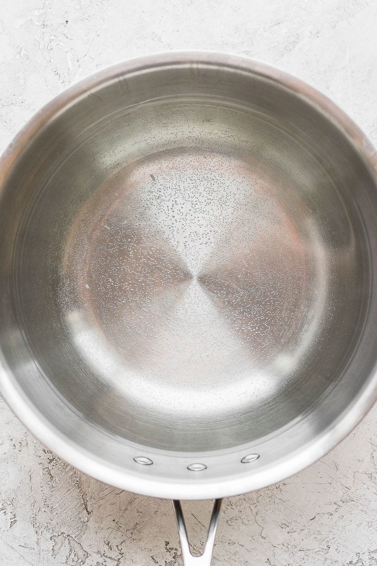 A saucepan with water in it that is just about to start boiling. 