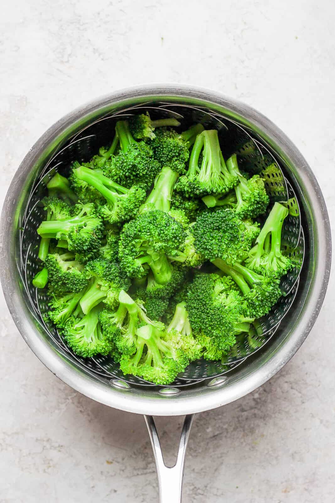 A saucepan with steamed broccoli inside.