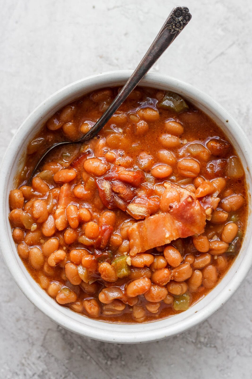 Smoked baked beans in a bowl with a spoon.
