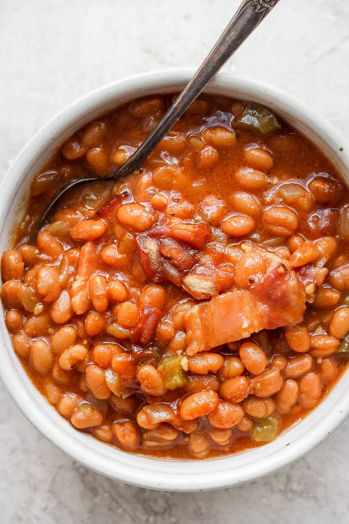 Bowl of smoked baked beans with a spoon sticking out. 