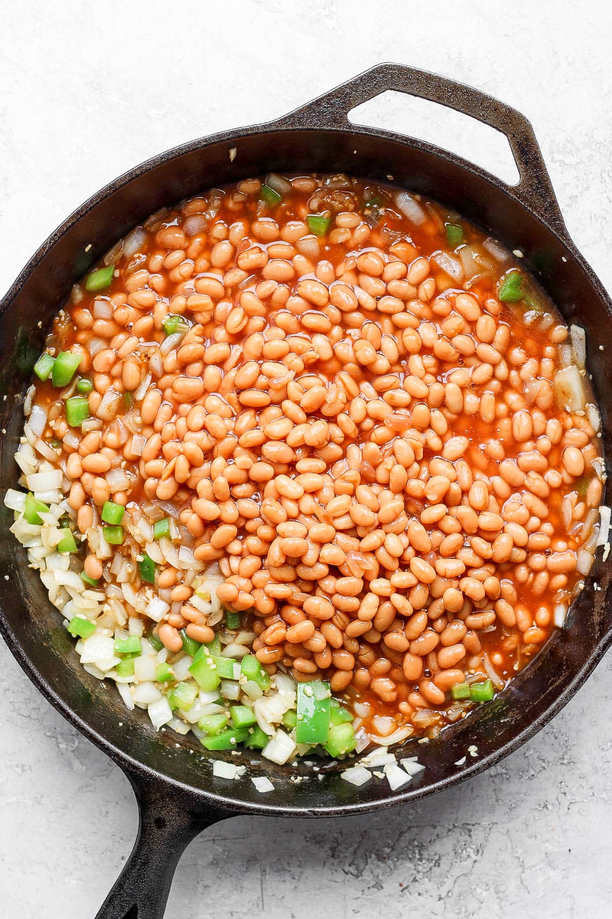 Ingredients for baked beans in a cast iron skillet. 