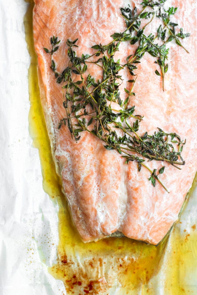 Close up of a piece of cooked salmon en papillote with melted ghee and thyme. 